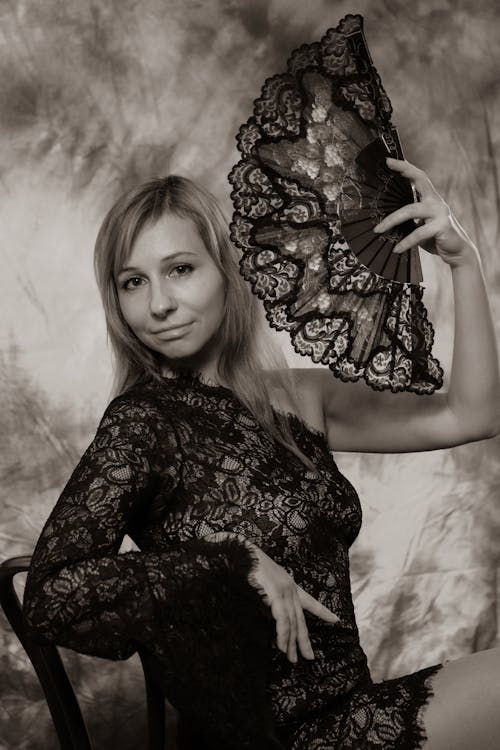 A woman in black lace holding a fan
