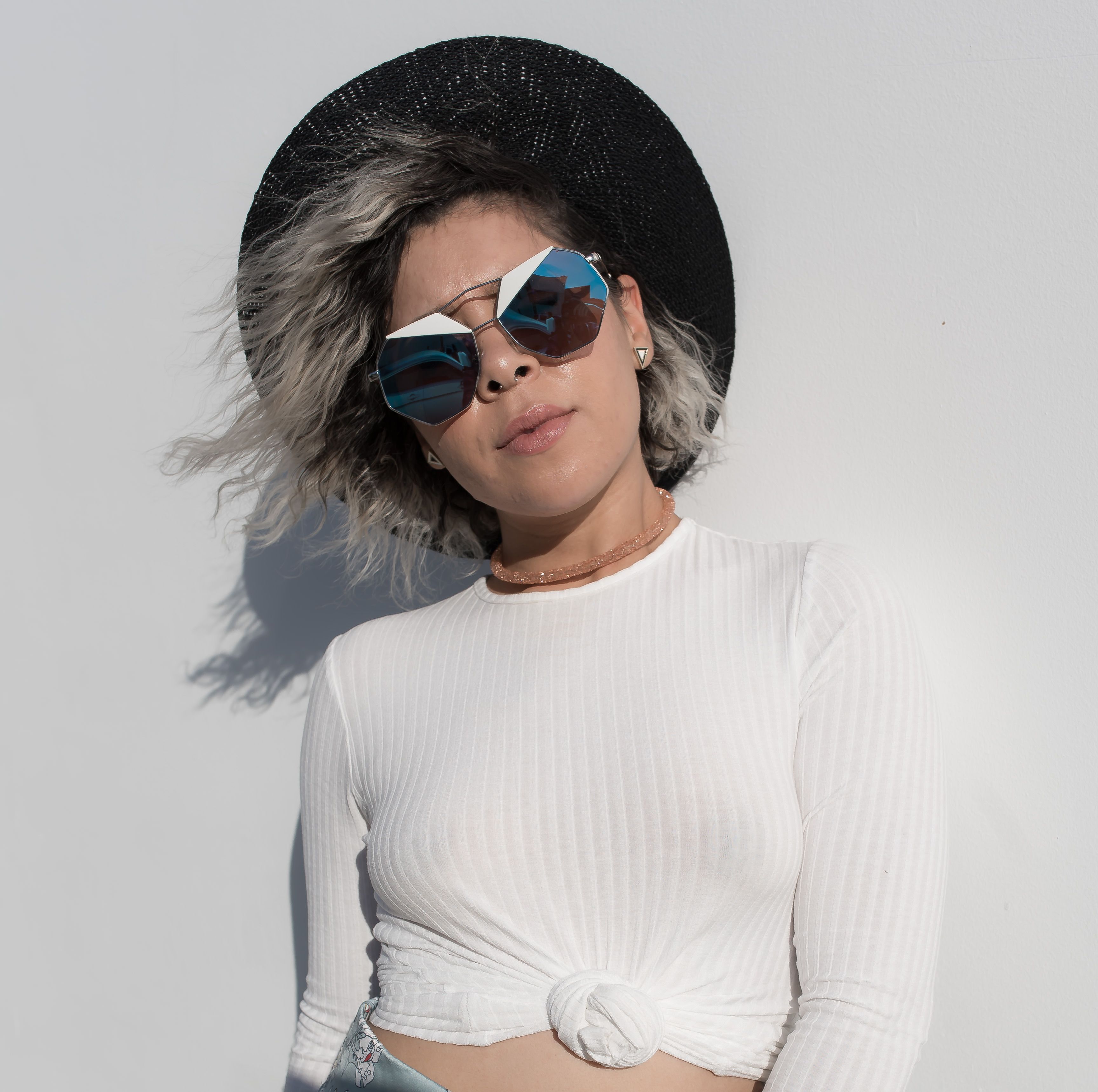 Fashionable woman posing outdoors in Los Angeles with sunglasses and a black sun hat.