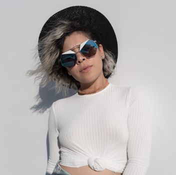 Fashionable woman posing outdoors in Los Angeles with sunglasses and a black sun hat.