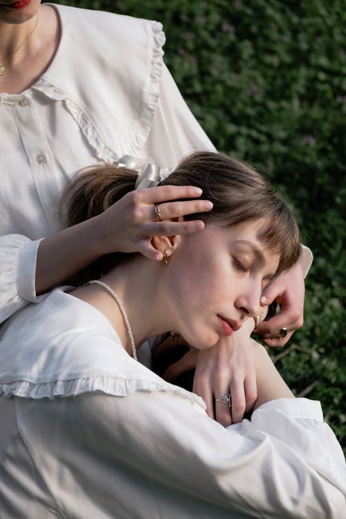 Two women in white sitting on the grass