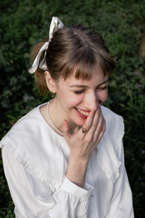 A woman is laughing while holding her hand to her mouth