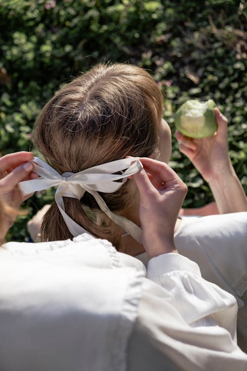 A woman is tying her hair with an apple