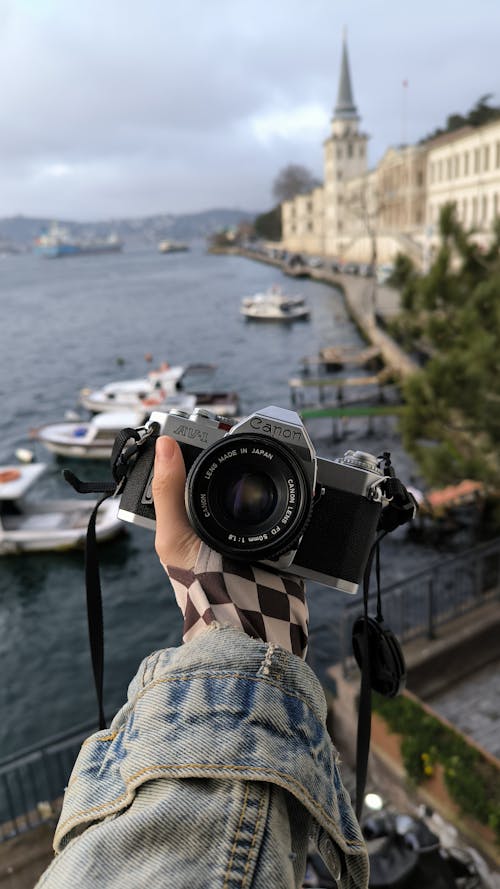 A person holding a camera over a body of water