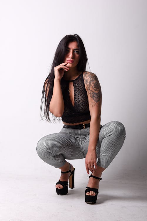 A woman in black pants and a top with tattoos