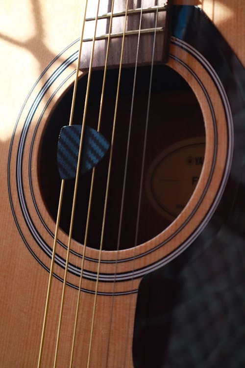 Free Pick Between String of Acoustic Guitar Stock Photo