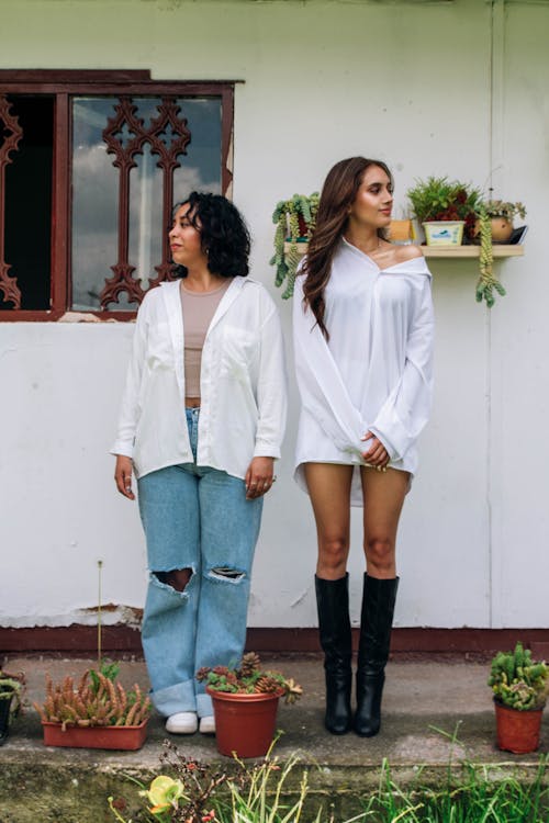 Two women standing outside of a house with plants