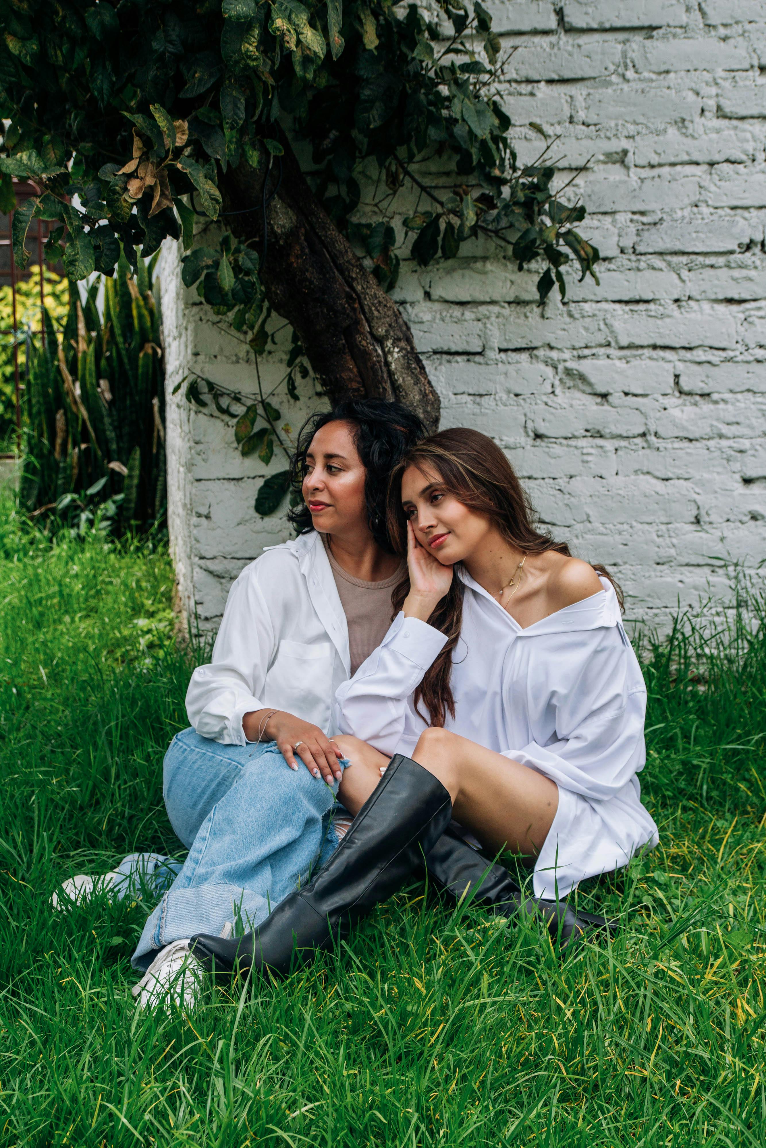 grátis Mulheres Morenas Em Camisas Brancas Posando Na Grama Perto Da Parede Branca Foto profissional
