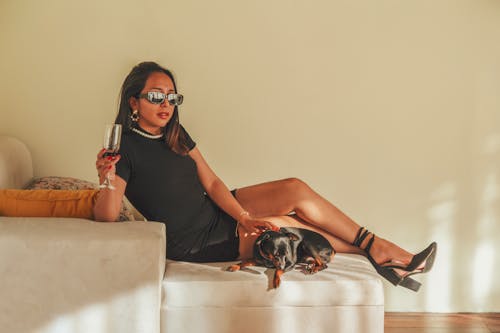 A woman in sunglasses sitting on a couch with a dog