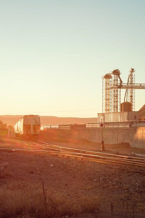 Factory Infrastructure near Train on Railway at Sunset