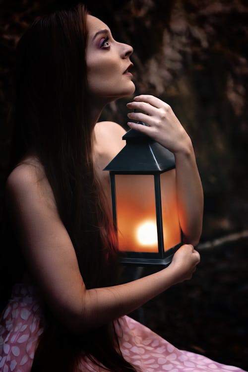 A woman holding a lantern in the woods