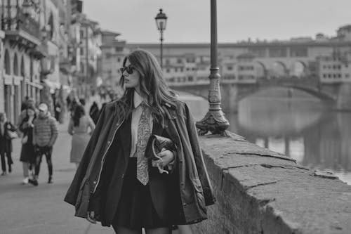 Fashionable woman strolls along Florence's Ponte Vecchio in a black and white portrait.