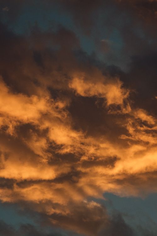 Free A stunning display of golden clouds illuminated by the sunset, creating a dramatic and serene sky scene. Stock Photo