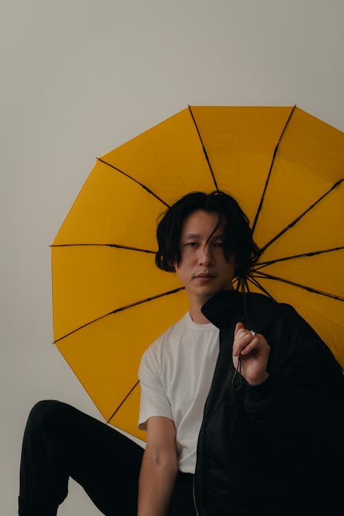 Kostnadsfri bild av asiatisk man, gult paraply, håller
