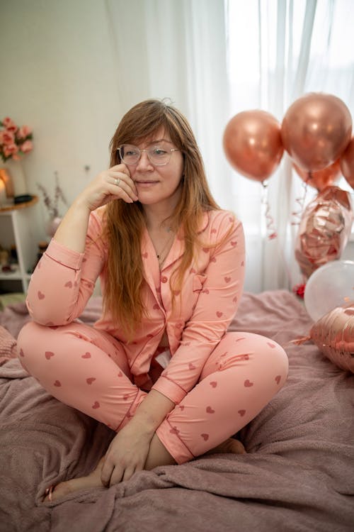 Woman in Pajamas with Hearts Sitting on Bed