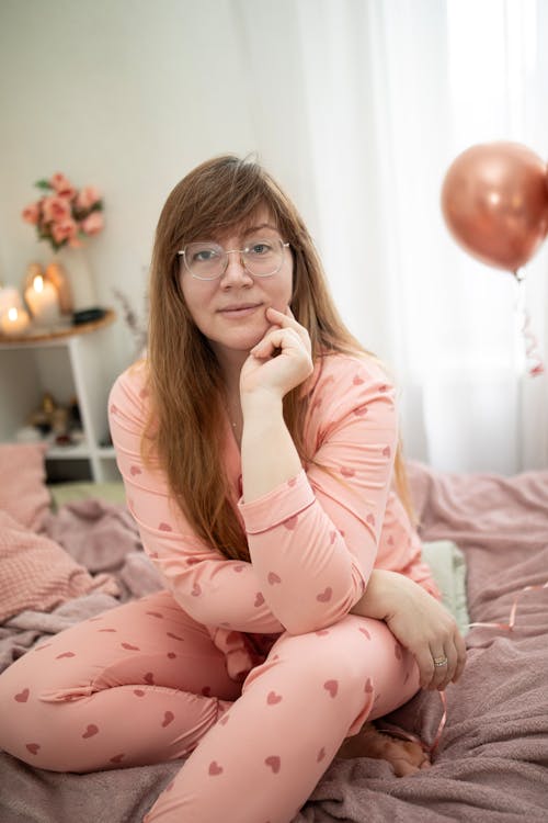 Sitting Woman in Pajamas with Hearts on Bed