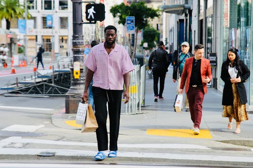 Man in Shirt and with Bags Crossing Street