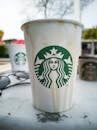 星巴克纸杯的特写，杯子上有滴水痕迹，放在户外桌子上