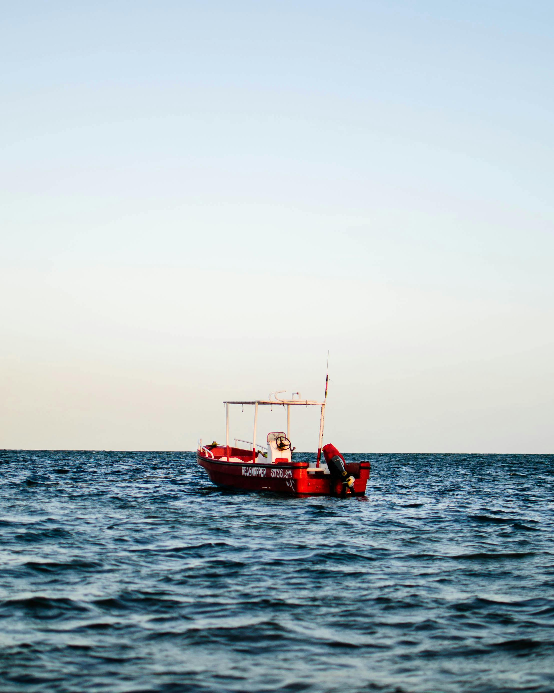 A red fishing boat floats on the tranquil Indian Ocean near Malindi, Kenya, on a clear summer day.