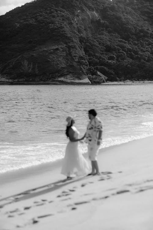 A black and white photo of a couple walking on the beach