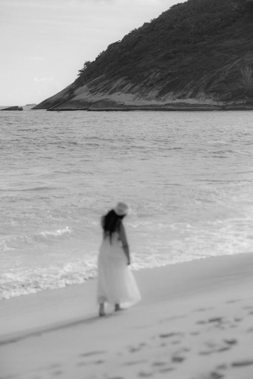 A woman in a white dress walking on the beach