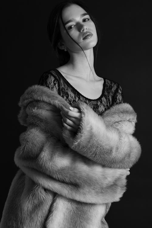 A woman in a fur coat posing for a black and white photo