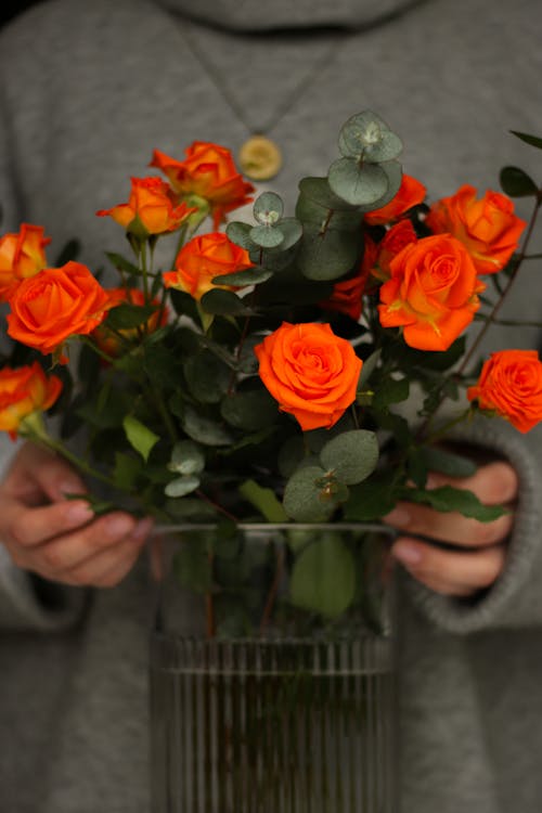 Woman Hands Holding Vase of Orange Roses