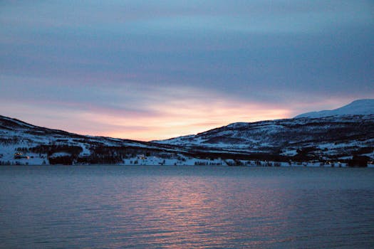 Peaceful winter sunset over a snow-covered landscape in Laksvatn, Norway.