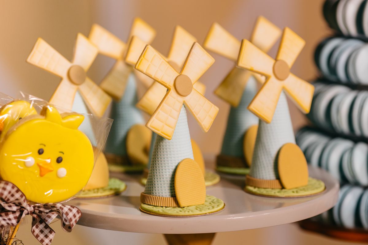 Vibrant windmill-shaped cupcakes and chick lollipops on a dessert table.