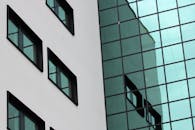 现代建筑立面的特写中，玻璃窗映出了城市环境