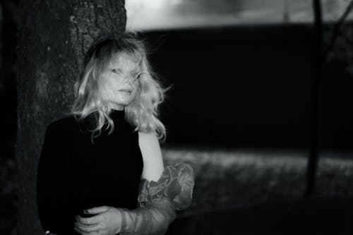 A woman in black and white standing next to a tree