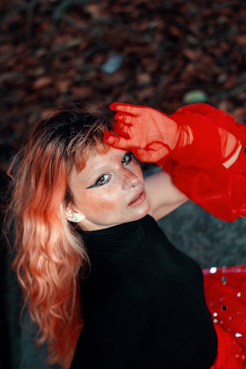 A woman with red hair and red gloves posing