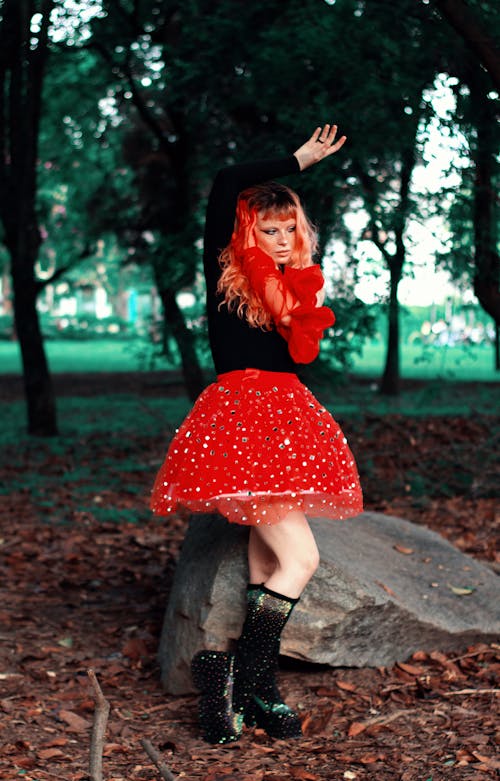 A woman in red and black skirt posing in the woods