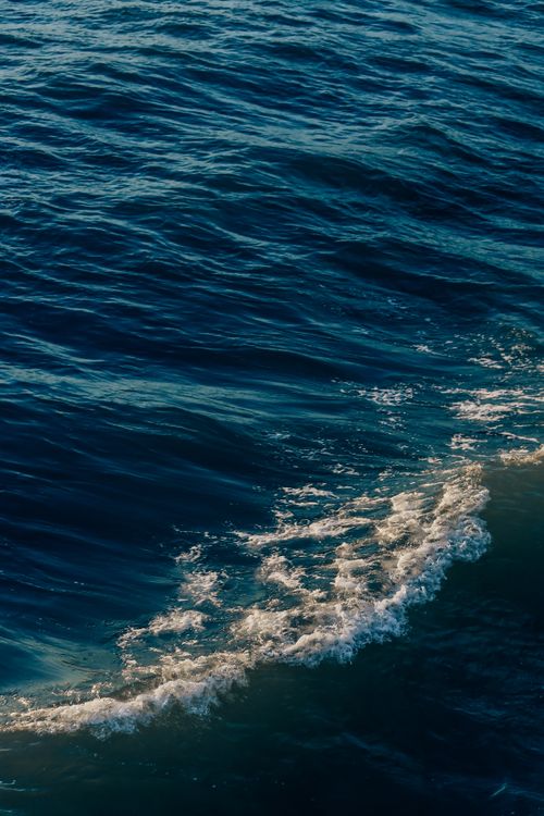 Free A calming view of ocean waves gently rolling under the warm, golden light of the day, capturing nature's beauty and tranquility. Stock Photo