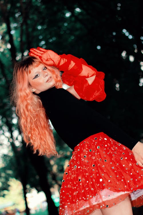 A woman with red hair posing in a park