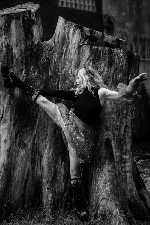 A woman is standing on top of a tree stump