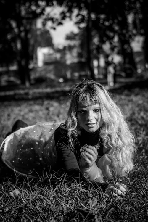A black and white photo of a young girl laying in the grass