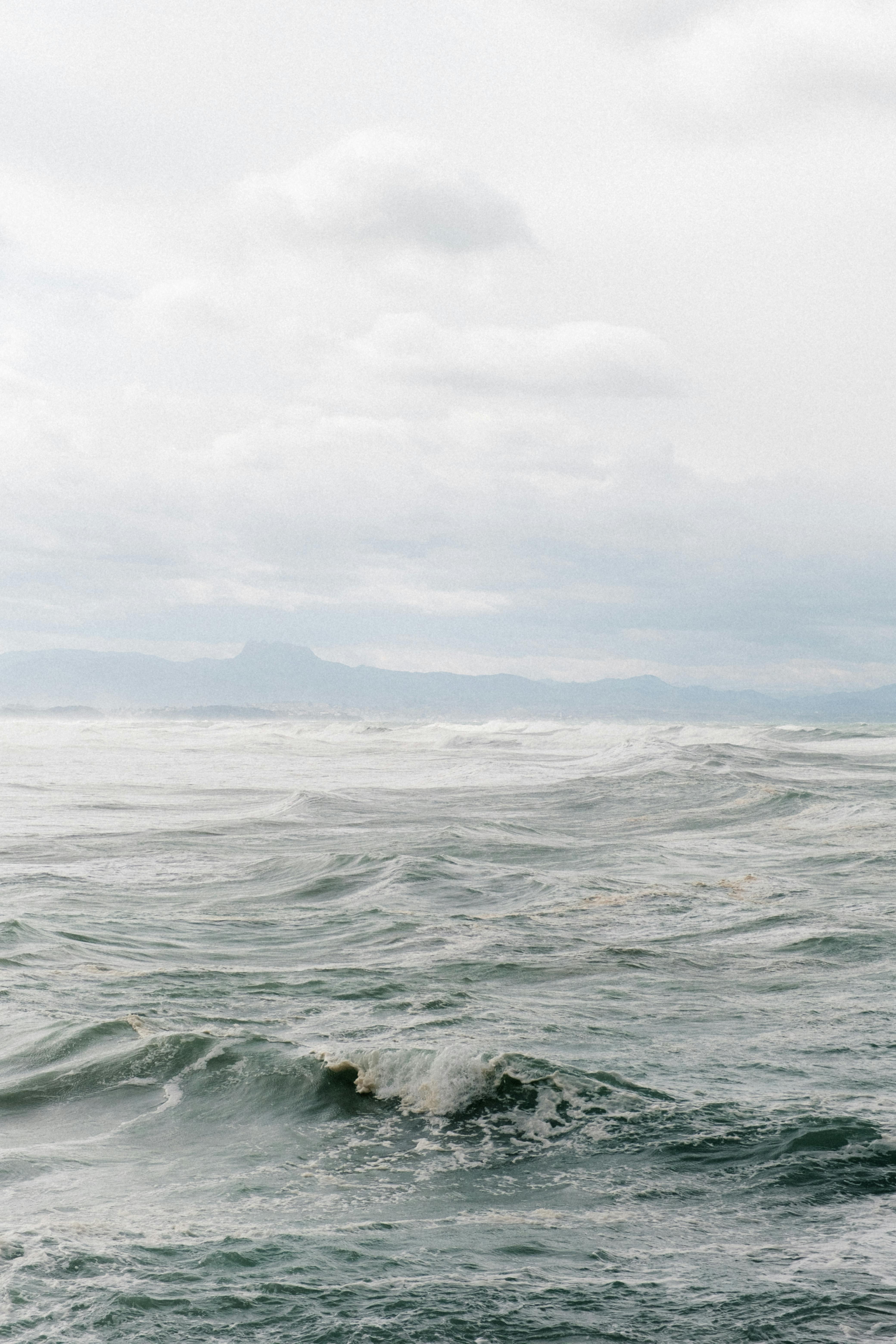 Moody seascape with rolling waves under an overcast sky, capturing coastal drama.