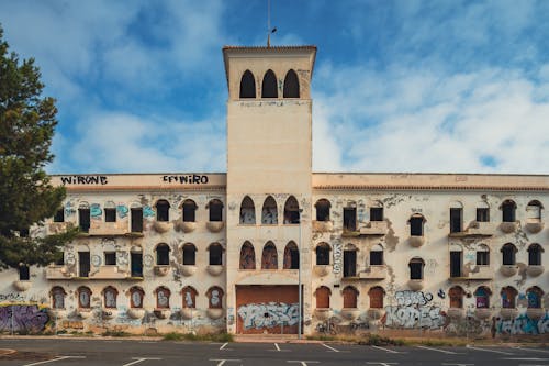 An old building with graffiti on it and a parking lot