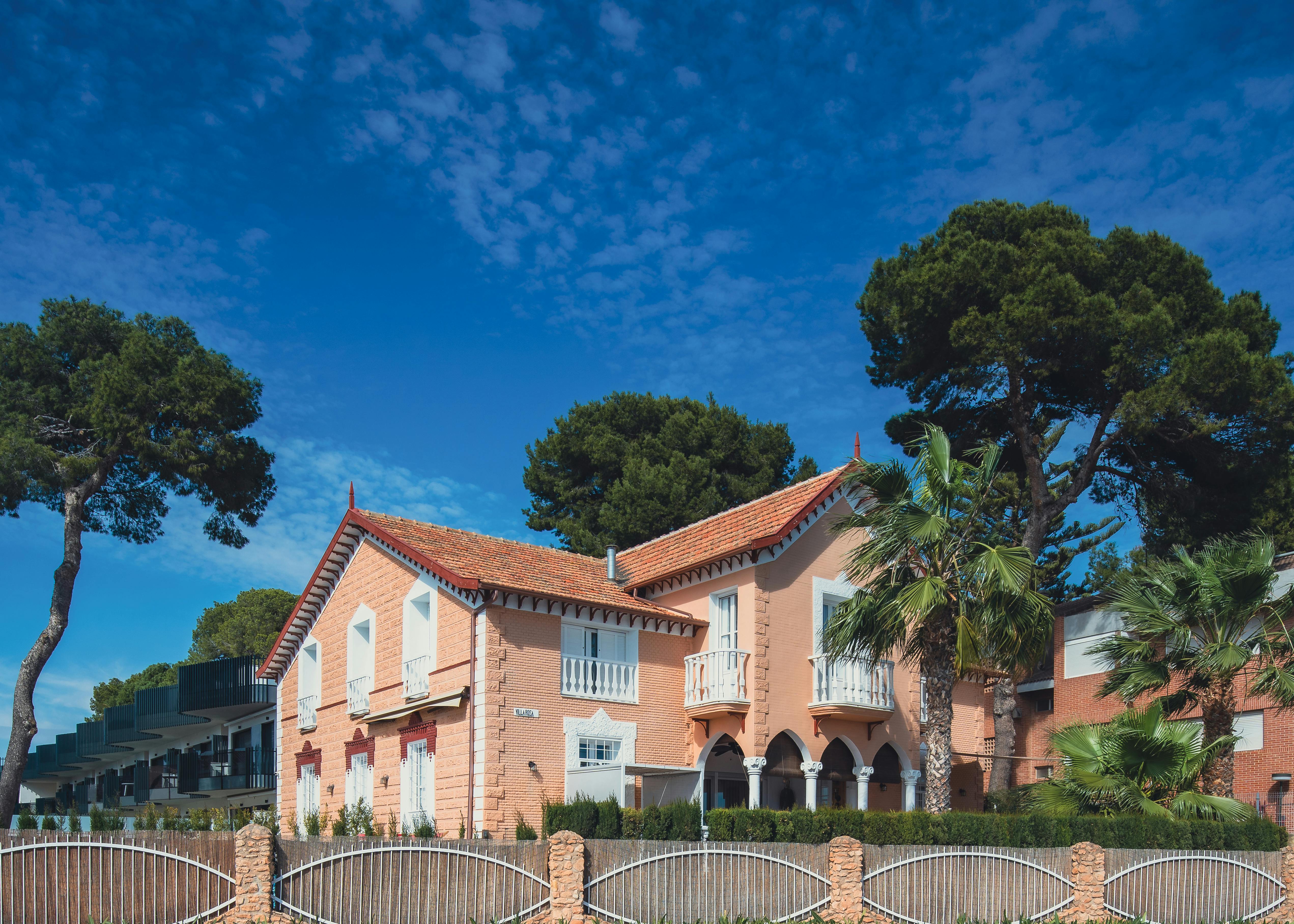 Picturesque villa in San Javier, Spain surrounded by lush trees and vibrant blue sky, ideal for travel enthusiasts.