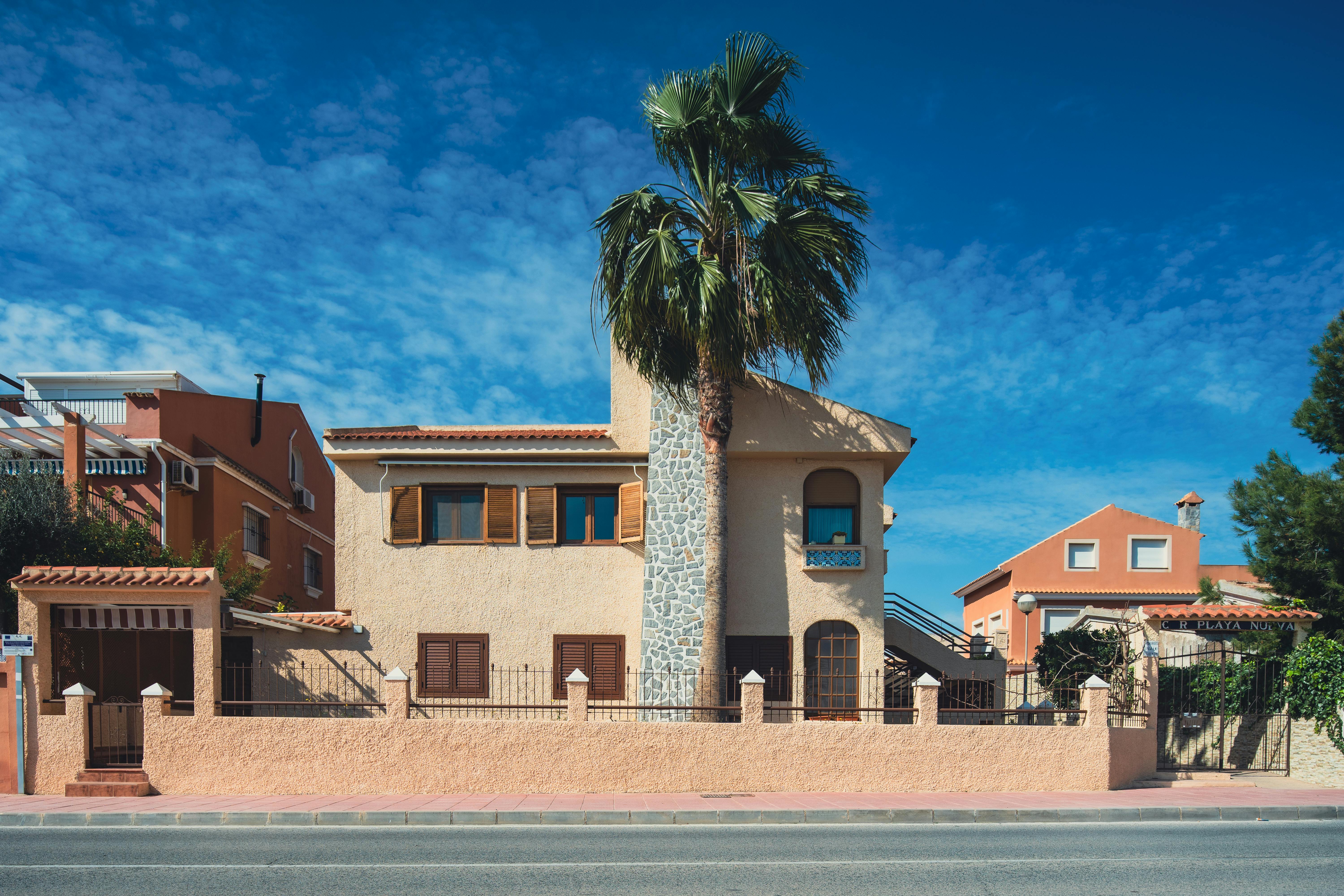 Beautiful Mediterranean-style house with palm tree in San Javier, Spain, under a vibrant blue sky.