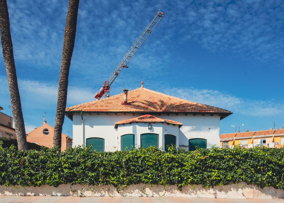 Beautiful house in San Javier, Spain, featuring a construction crane and palm trees under a clear blue sky.
