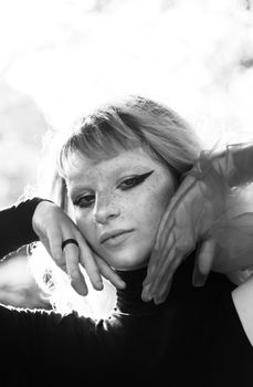 Elegant black and white portrait of a freckled woman with dramatic makeup and tulle accent.