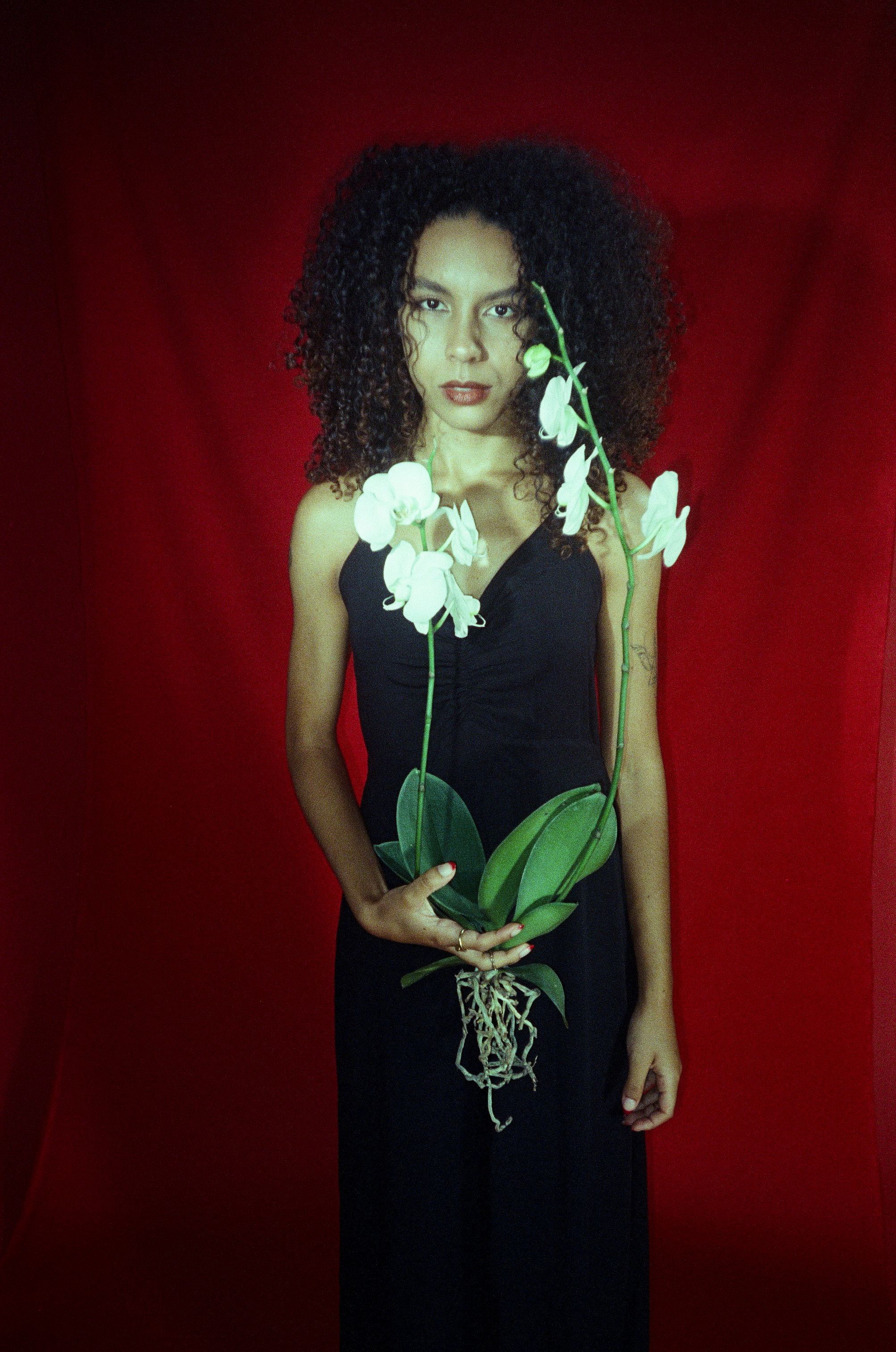 Woman in Black Dress Standing with Flowers · Free Stock Photo