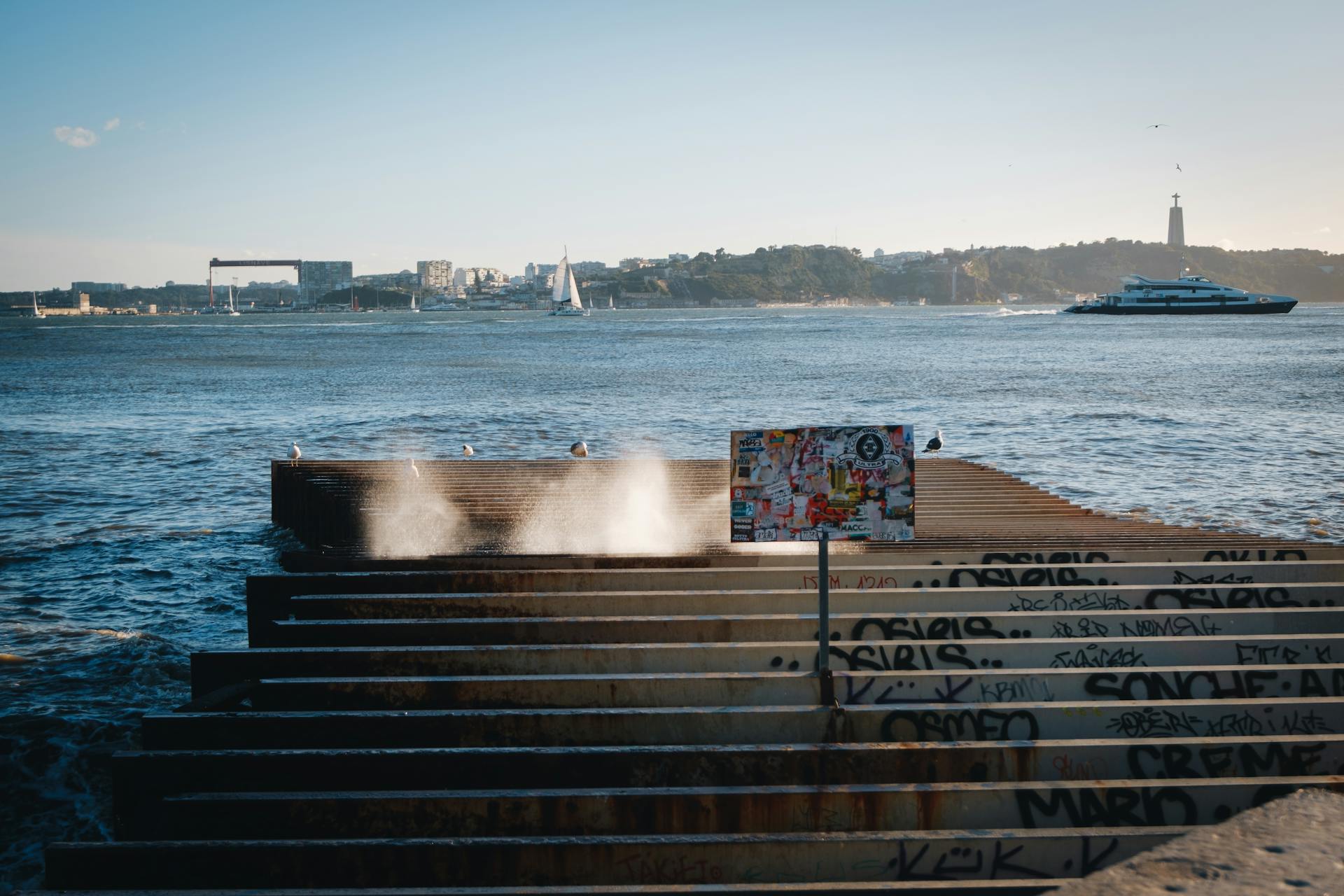 Unique waterfront view in Lisbon featuring graffiti, boats, and city skyline.
