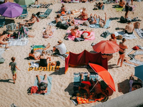 A large group of people on a beach with umbrellas