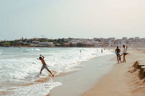 People walking on the beach near a city