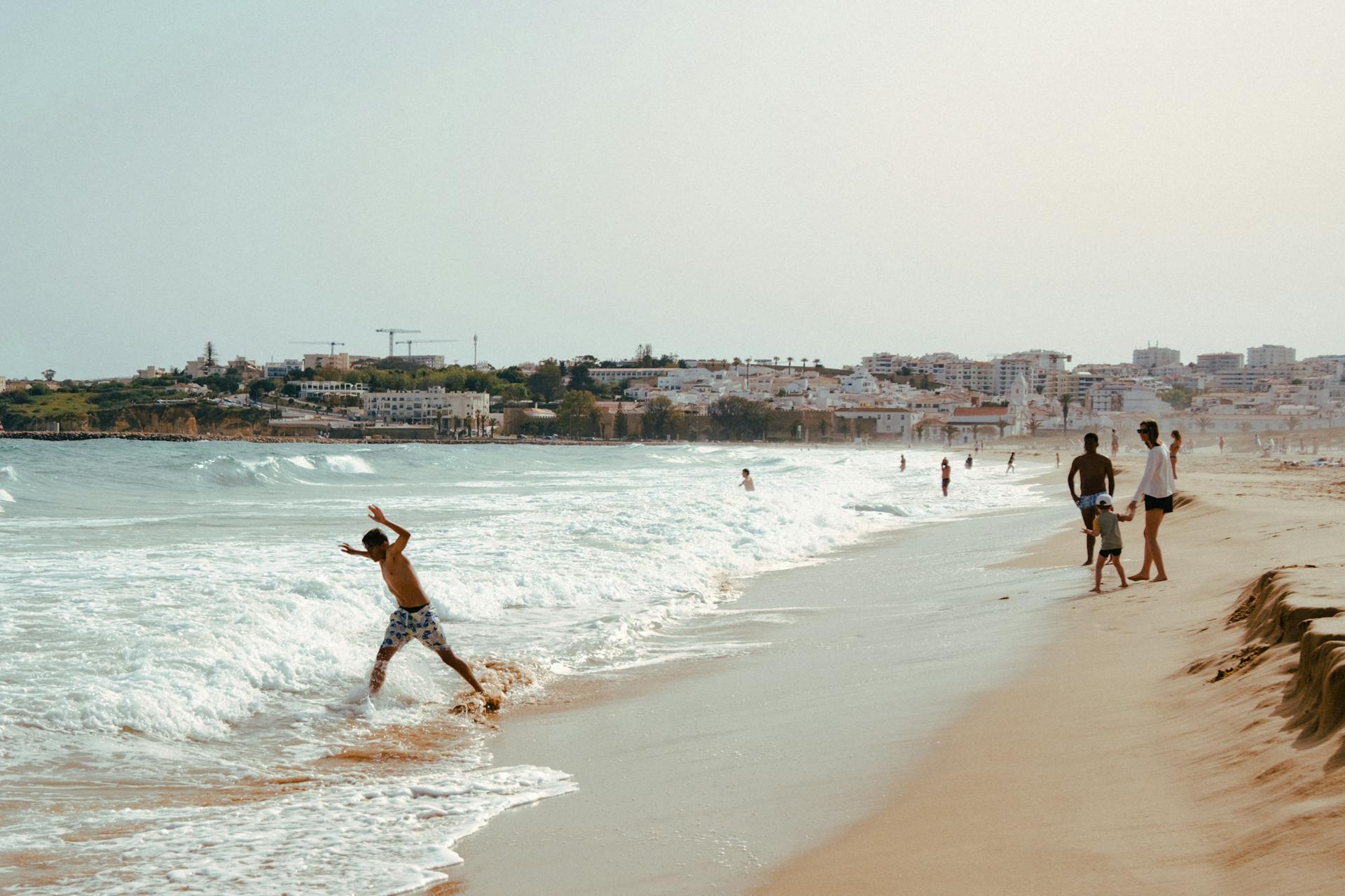 A lively summer day at Lagos beach in Portugal with families enjoying the waves and sunshine.