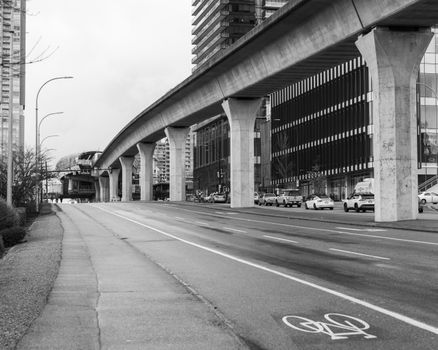 Monochrome view of Vancouver's urban street with viaduct and bike lane.