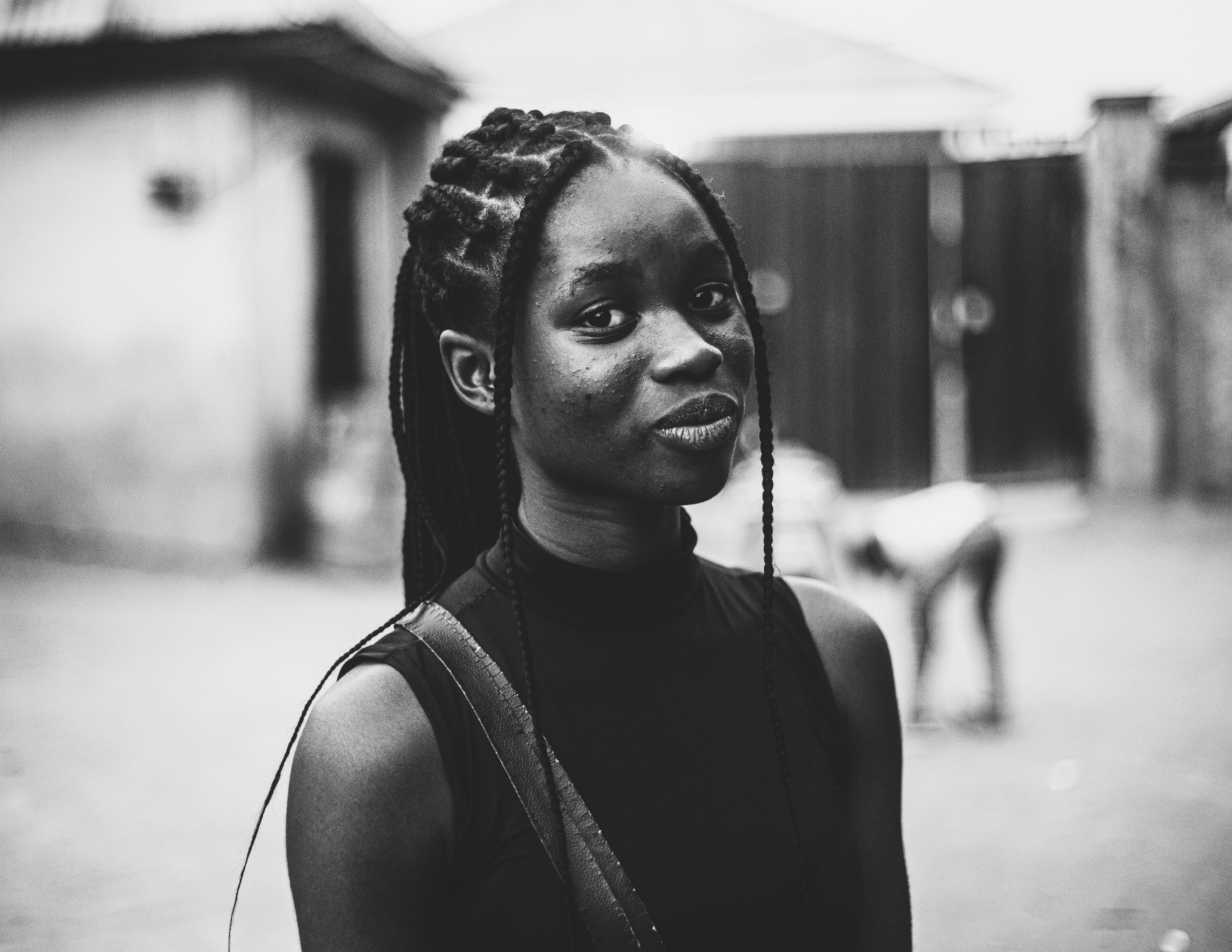 Charming portrait of a young woman smiling outdoors in Abuja, Nigeria. Black and white photography.