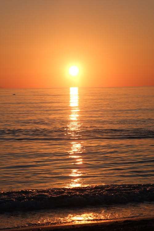 Free A sunset over the ocean with a person walking on the beach Stock Photo